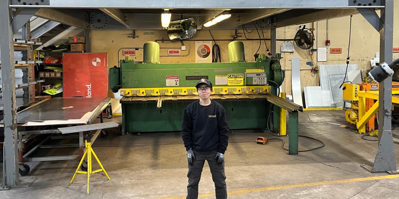 Image shows Rebecca Suen, sheet metal apprentice, working in a sheet metal fabrication shop.