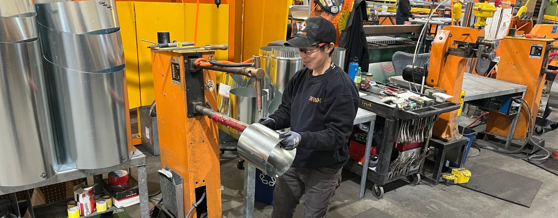 Image shows Rebecca Suen, sheet metal apprentice, working in a sheet metal fabrication shop.